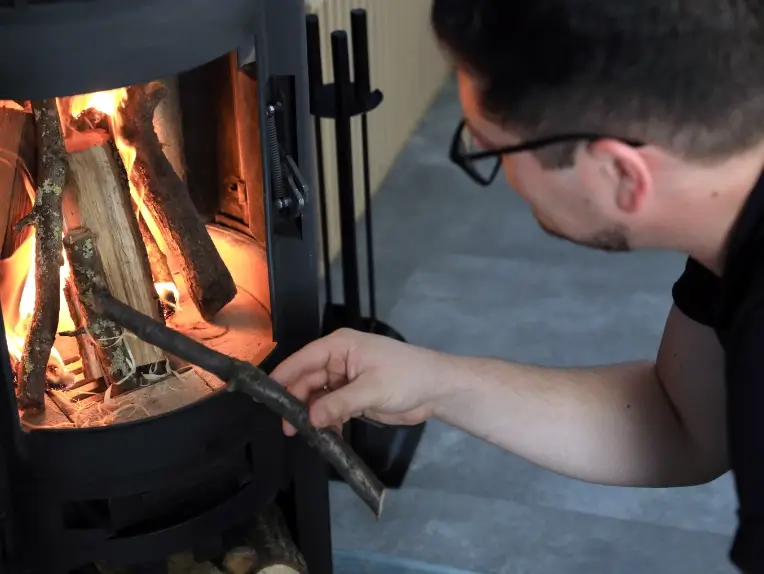 Hendrik legt Feuerholz in den büroeigenen Kaminofen für den nächsten Termin nach.